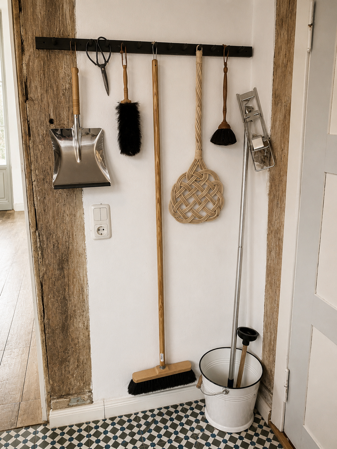 Household brushes, brooms and a bucket arranged on a wall rail in the Brandenburg home