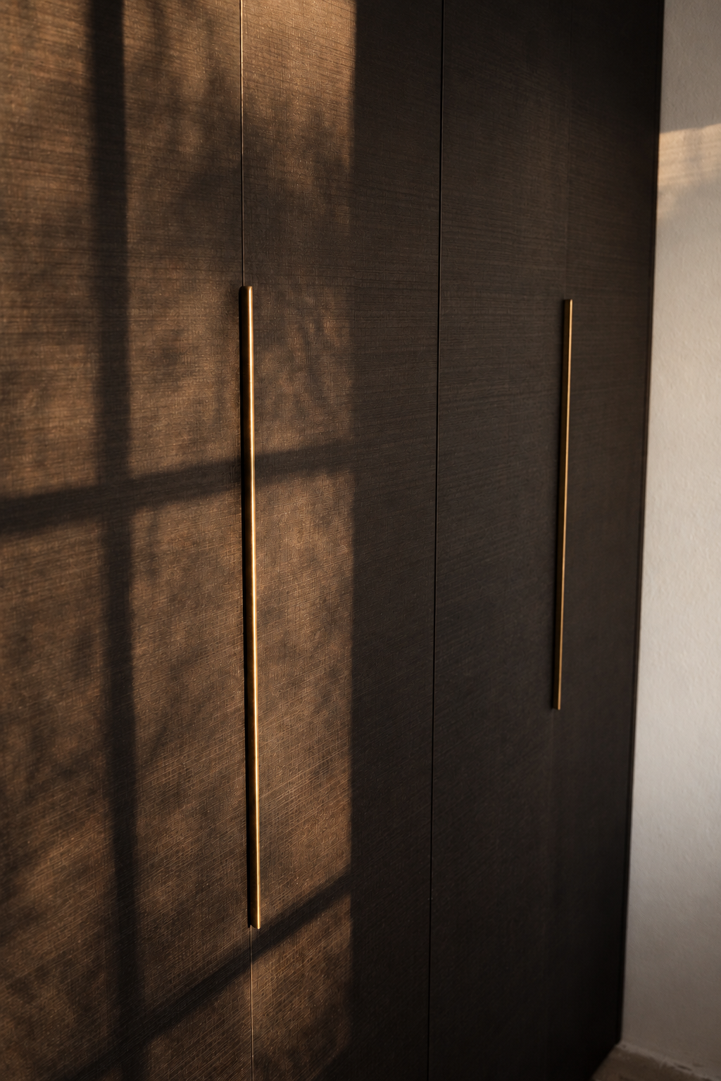 Dark timber cabinetry with slender brass handles in warm afternoon light in the Brandenburg home