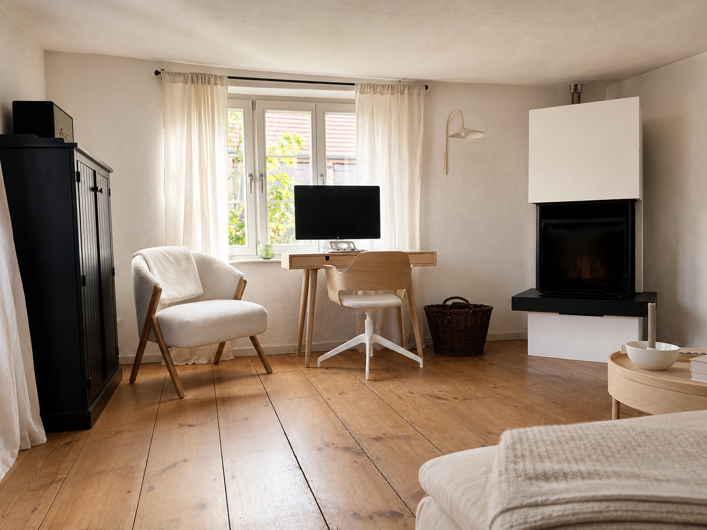 Living room in the Brandenburg home with a timber desk, pale armchair and fireplace