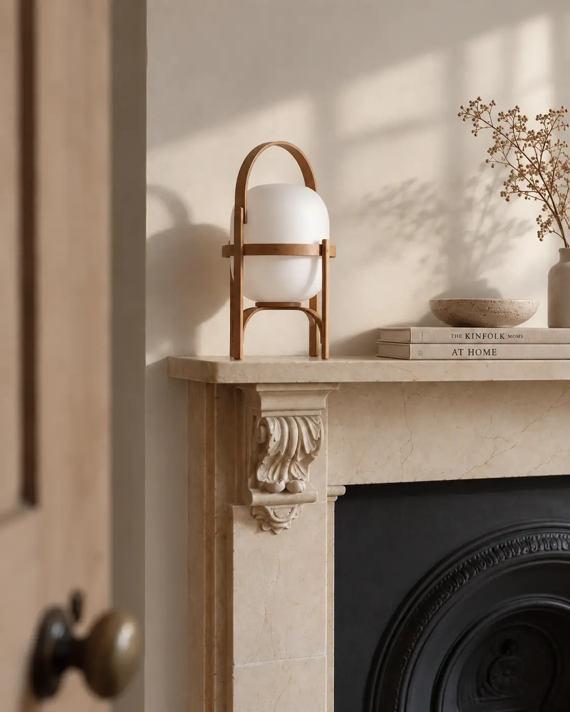 Marble mantelpiece in the London townhouse with a rattan table lamp and books