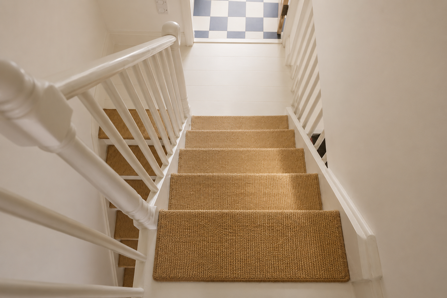 Staircase of the London townhouse with a natural fibre runner and chequered landing