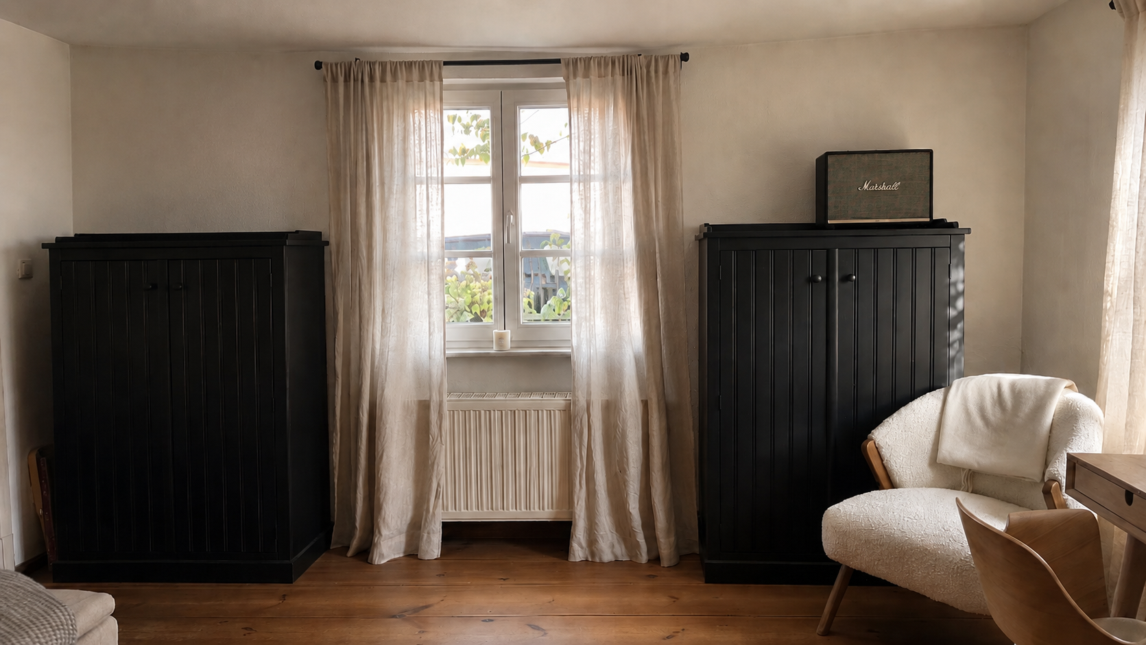 Living room in the Brandenburg home with dark cupboards, linen curtains and a pale armchair