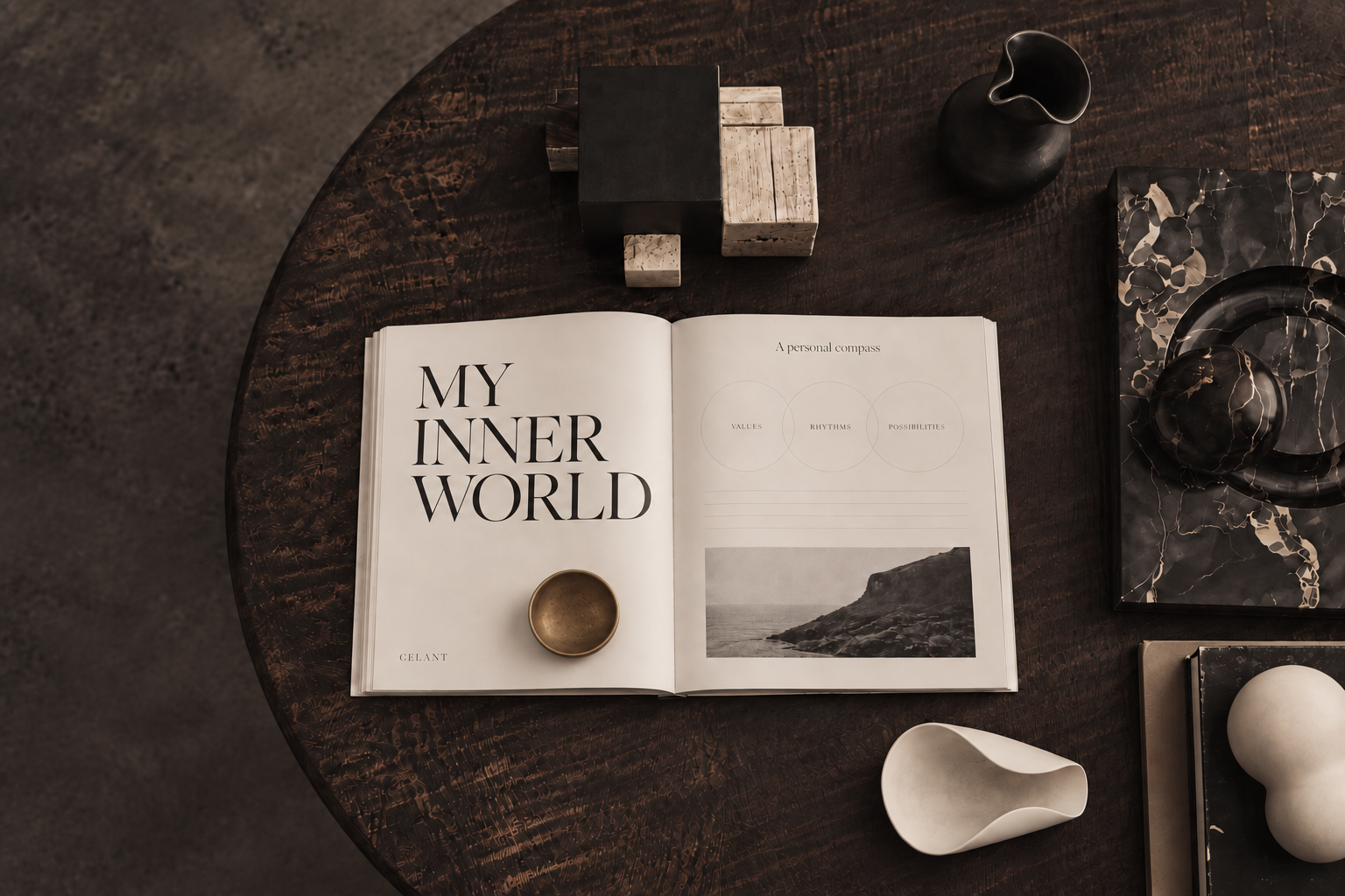 Open CELANT journal arranged with sculptural objects on a dark timber table