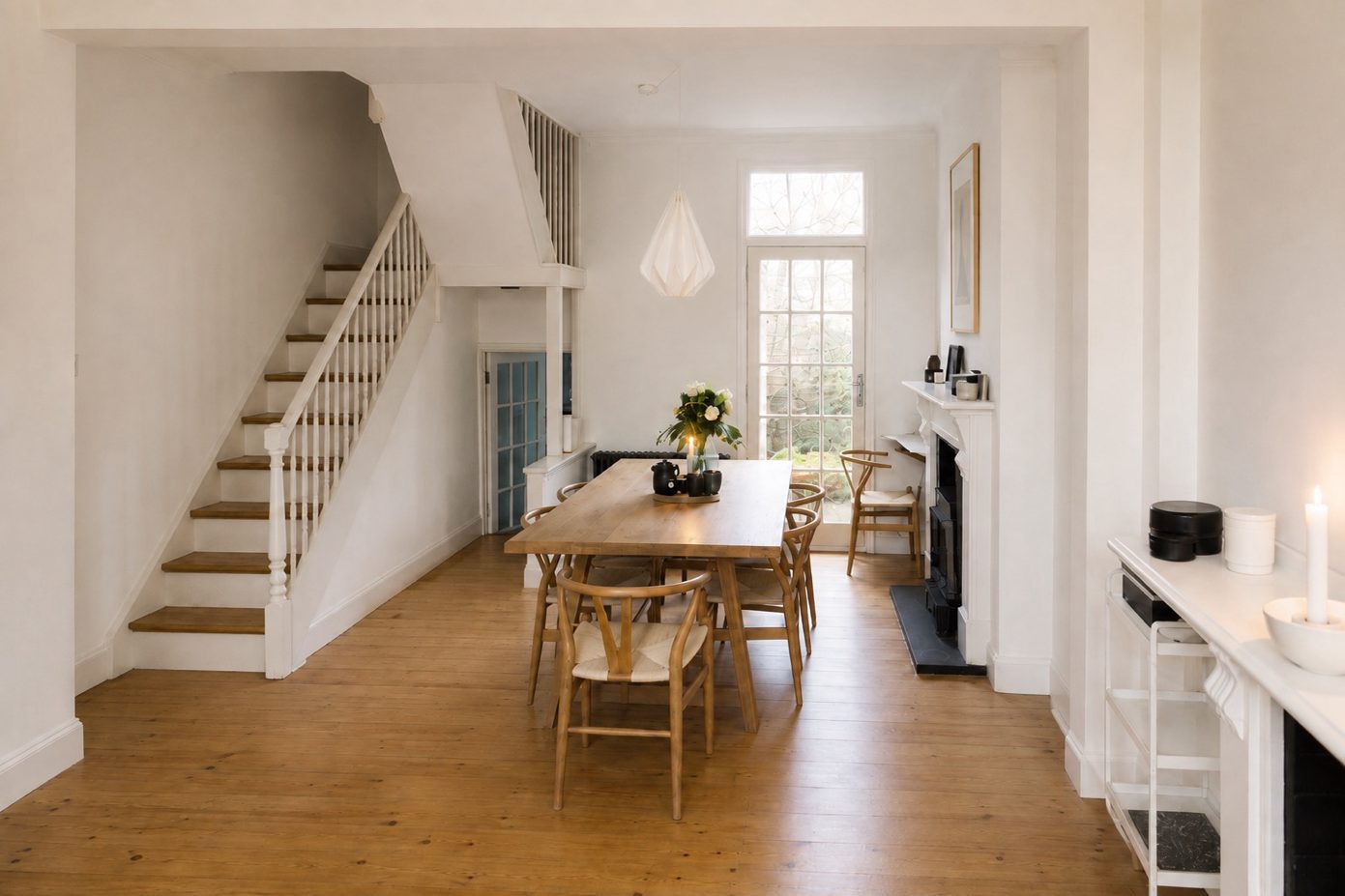 Open-plan dining area of the London townhouse with pale walls, timber floor and daylight from the rear window