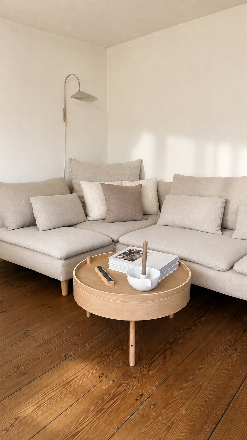 Pale linen sofa and round timber coffee table in a light-filled corner of the Brandenburg home